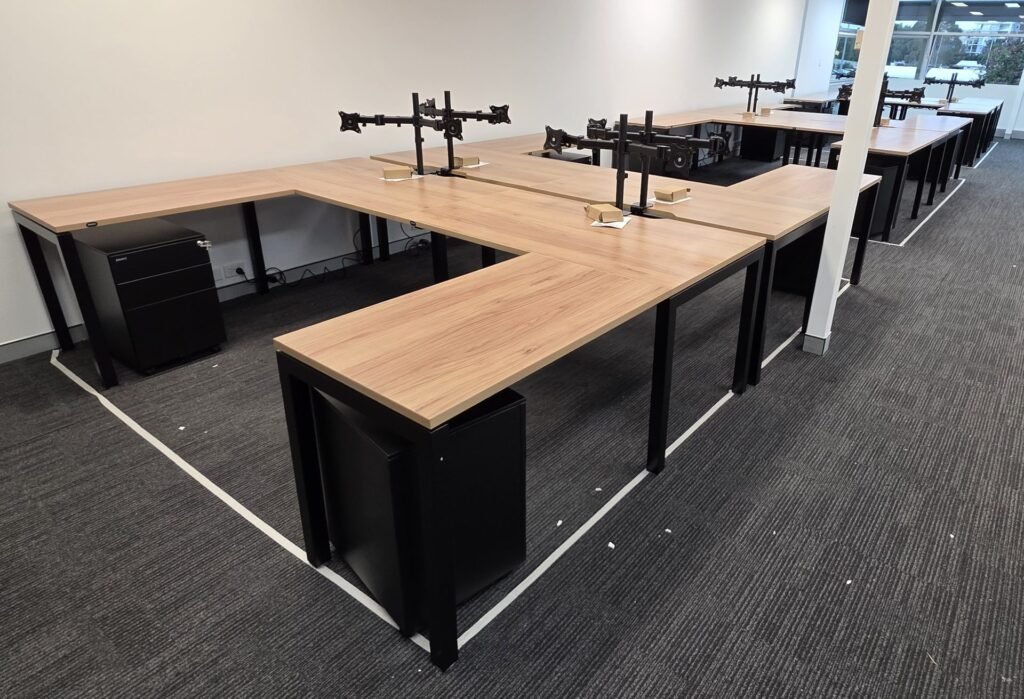 Bank of assembled timber office workstations with monitor arms